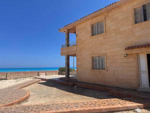 a building on the beach with the ocean in the background at Beachfront Villa Sea View First Row in Dawwār ‘Abd Allāh