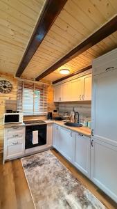 a kitchen with white cabinets and a wooden ceiling at Mountain Paradise House in Žabljak
