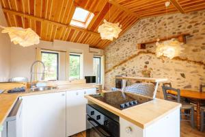 a kitchen with white cabinets and a wooden ceiling at Maison de Charme - Écrin de Nature in Saint-Privat
