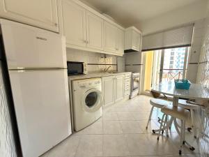 a kitchen with a white refrigerator and a dishwasher at Casa Nau C in Armação de Pêra