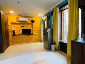 a room with a yellow wall with a refrigerator at Nina's Aqua - Private Pool Villa & Plunge Pool Studios, Anjuna in Anjuna