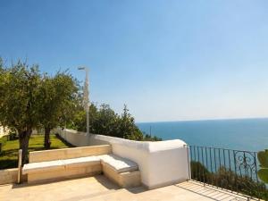 a bench on a balcony with the ocean in the background at La Locanda Del Carrubo in Mattinata +56 photos