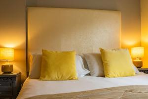 a bedroom with a bed with yellow pillows and two lamps at Bagshaw Lodge in Bakewell +44 photos