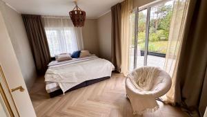 a bedroom with a bed and a chair and a window at Kõpu Seaside Getaway in Rannaküla