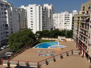 a pool in the middle of a city with tall buildings at Casa Nau C in Armação de Pêra
