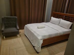 a bedroom with a bed with a chair and a pillow at City Link Complex Ressort in Mwanza
