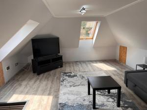 a living room with a couch and a tv at Filkes Rezidence in Filkeháza