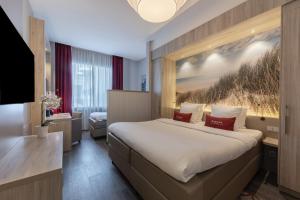 a hotel room with a large bed and a desk at Ramada The Hague Scheveningen in Scheveningen +101 photos