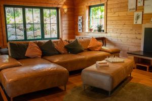 a living room with a brown leather couch and a table at HolzHaus AusZeit am Küppel & Bright Collection in Gersfeld