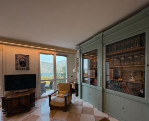 a living room with a tv and a chair and a window at Holiday Home Lake Orta in Pettenasco