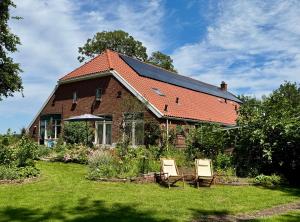 a house with a roof with two chairs in the yard at Slaaphutje BuitenWedde Westerwolde in Wedde