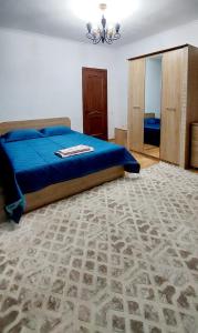 a bedroom with a bed with blue sheets and a carpet at Яншина 6 in Qyzylorda +6 photos