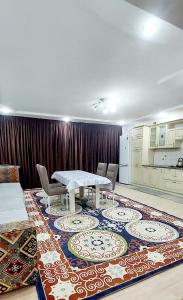 a dining room with a table and chairs on a rug at Яншина 6 in Qyzylorda