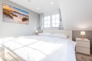 a white bedroom with a white bed and a window at Haus Breslauer Straße 22a in Süderende