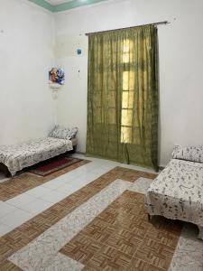 a room with two beds and a green curtain at Residence wafa 1 in Jijel