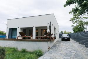 a white house with chairs and a car on a driveway at Wild River 2 in Neporotovo