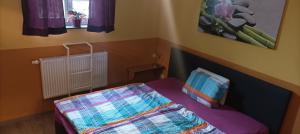 a small bedroom with a bed with a blanket on it at Pension Johnnys in Görlitz +17 photos