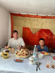 two men sitting at a table with food at Ak Bulak in Kurmenty