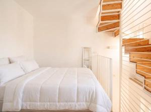 a white bedroom with a bed and a staircase at Casa con Vista a POLIGNANO a Mare in Polignano a Mare