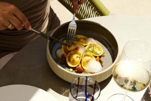 a person holding a fork and knife in a bowl of food at Alpiana Dolce Vita Mountain Resort & SPA in Vollan