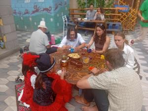 a group of people sitting around a table eating food at Guest House Aruuke in Naryn