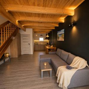 a living room with a couch and a staircase at Domki Osada Kalinowa Nowęcin Łeba Sauna in Łeba