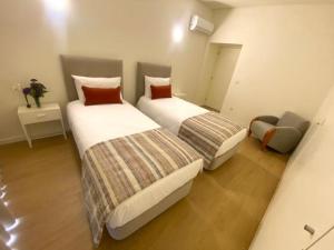 a bedroom with two beds and a chair at Casa Mamosteira Apartamento da Eira in Sandim