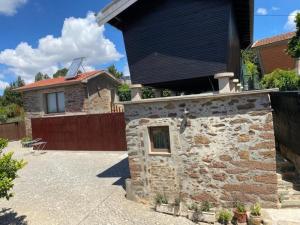 a stone house with a black roof and a yard at Casa Mamosteira Apartamento da Eira in Sandim