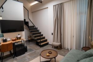 a living room with a tv and a staircase at ASO Hotel - Historic Raisin Warehouse 1928 in Kalamata