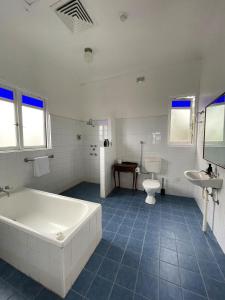 a bathroom with a tub and a toilet and a sink at The Old Vic Hotel in Canowindra +32 photos