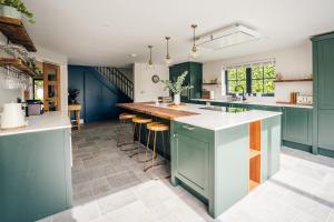 a kitchen with blue cabinets and bar stools at Mill Farm in Gamlingay +8 photos