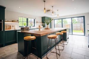 a kitchen with green cabinets and a counter with stools at Mill Farm in Gamlingay