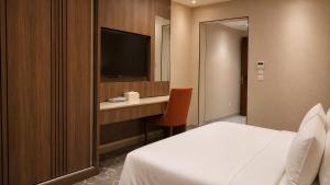 a hotel room with a bed and a desk with a television at NARS Plus Serviced Apartments - Al Nuzha in Jeddah