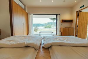 two beds in a room with a large window at MANANI - Vacation STAY 16612v in Nago