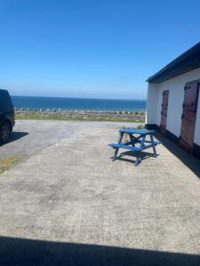 a picnic table sitting in a parking lot near the ocean at The Tackroom in Fanore