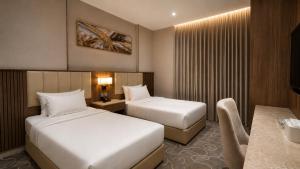 a hotel room with two beds and a desk at NARS Plus Serviced Apartments - Al Nuzha in Jeddah +23 photos