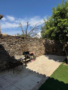 a stone wall with a picnic table and a grill at Casa Limón in Bodonal de la Sierra