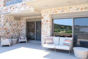 a patio with a couch and chairs on a stone wall at Stone Luxury Suites in Agioi Apostoli