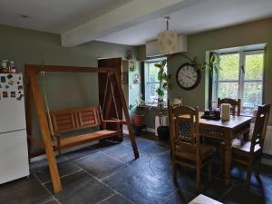 a kitchen with a table and chairs and a clock on the wall at Tranquil Woodland Cottage by river Wye in Lydbrook