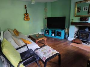 a living room with a couch and a flat screen tv at Tranquil Woodland Cottage by river Wye in Lydbrook