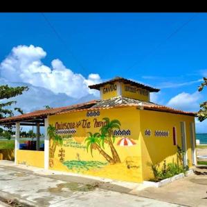 a yellow building with a palm tree painted on it at Recanto Tia Nena in Araruama