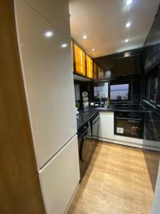 a kitchen with a white refrigerator and a wooden floor at Bouchareb résidences in Quşaybat al Madyūnī +4 photos