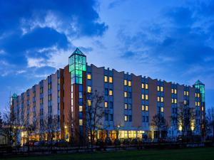 a building with a lit up facade at night at Sunday Hotel Leipzig-Halle in Landsberg OT Peißen