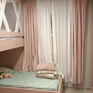 a bed with pink and white curtains in a room at Casa familiar in Piên
