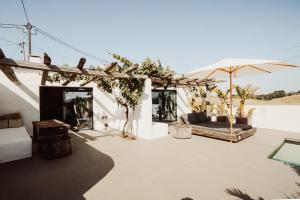 a patio with a couch and an umbrella at Suites Daldeia - Suite 1 in Azueira