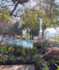 a swimming pool in a garden with rocks and trees at Die Boord Guesthouse in Crocodile Valley Estates