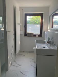 a white bathroom with a sink and a window at Refugium - central, quiet apartment with terrace in Frankenberg