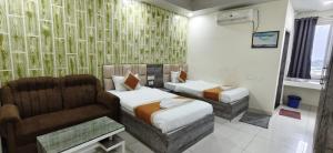 a hotel room with two beds and a couch at Hotel Glacier in Arāria +32 photos