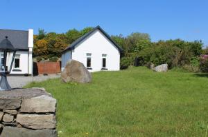 a white house with a rock in the yard at Renvyle 197 Tullycross Chalet in Renvyle