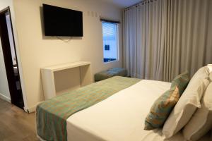 a hotel room with a bed and a flat screen tv at Hz Hotel in Patos de Minas